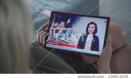 Tablet screen shows news broadcast about US elections with female newscaster Tablet screen shows news broadcast about US elections with female newscaster 116611639