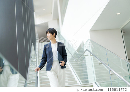 A woman in a suit walking down an office corridor A woman in a suit walking down an office corridor 116611752