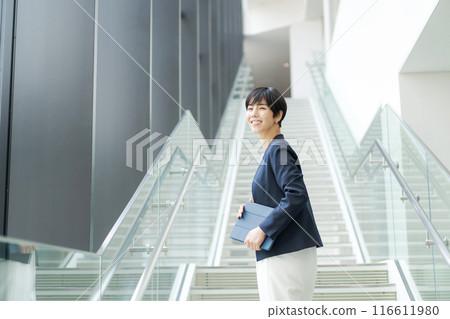 A woman in a suit climbing the stairs in an office 116611980