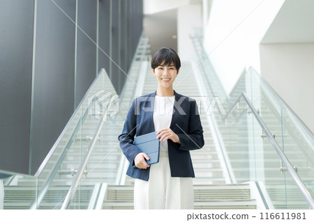 A woman in a suit climbing the stairs in an office A woman in a suit climbing the stairs in an office 116611981