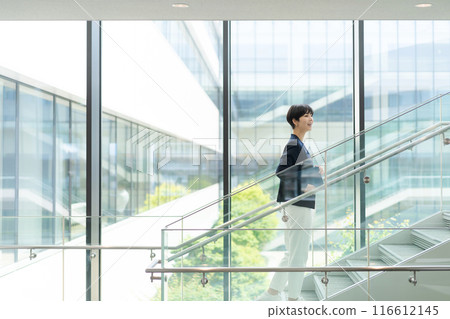 A woman in a suit walking in an office building 116612145