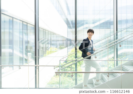 一位穿著西裝的女士在辦公大樓內行走 116612146