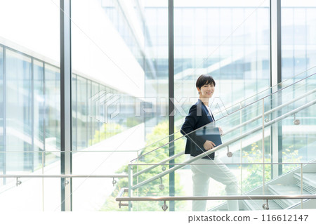 一位穿著西裝的女士在辦公大樓內行走 一位穿著西裝的女士在辦公大樓內行走 116612147