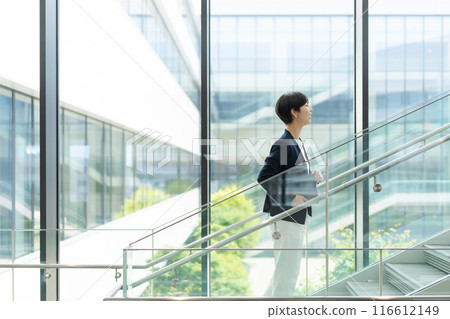A woman in a suit walking in an office building 116612149
