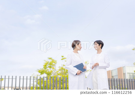 身穿白大褂的婦女在醫院屋頂上交談 116612256