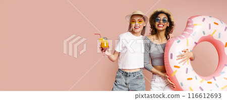 This image shows two happy friends posing with a donut pool float on a pink background. Both are smiling and wearing sunglasses. This image is perfect for representing summertime fun and friendship. 116612693