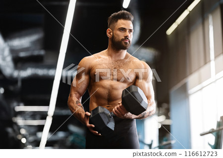 Sport and motivation. Muscular athlete with naked torso exercising with dumbbell in gym, free space Sport and motivation. Muscular athlete with naked torso exercising with dumbbell in gym, free space 116612723
