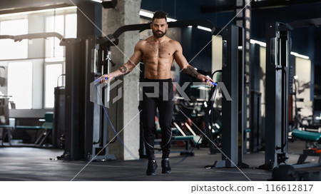 Best cardio workout. Sporty muscular man with perfect body training with skipping rope in gym interior, free space Best cardio workout. Sporty muscular man with perfect body training with skipping rope in gym interior, free space 116612817