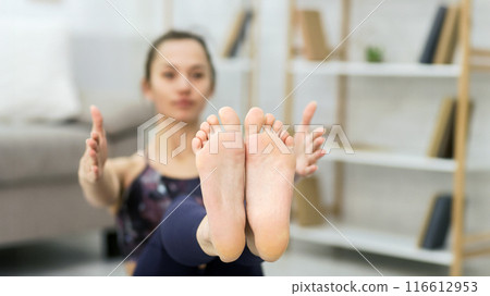 Girl doing fitness exercise for abs on floor, focus on feet. Full Boat pose Girl doing fitness exercise for abs on floor, focus on feet. Full Boat pose 116612953