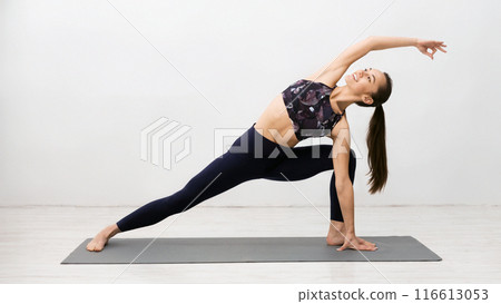 Girl Practicing Yoga, Stretching In Extended Side Angle Pose Over Light Brick Wall Girl Practicing Yoga, Stretching In Extended Side Angle Pose Over Light Brick Wall 116613053