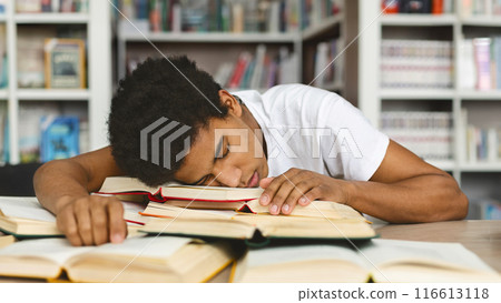Sleeping at library. Tired african american guy napping on books stack, being exhausted during preparing for exams 116613118