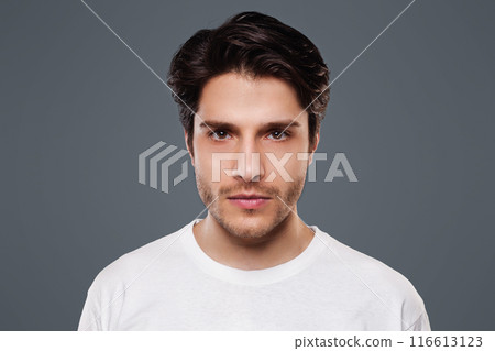 Confident man. Young millennial guy seriously looking at camera, grey background 116613123