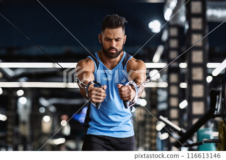 A man with a beard is working out on a cable machine at the gym. 116613146