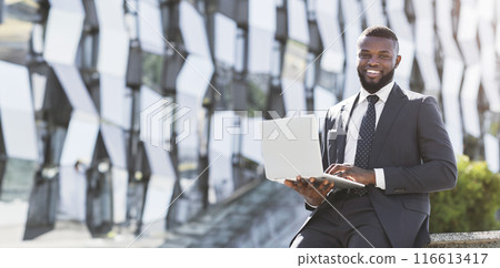 Young Black Entrepreneur Man Using Laptop Computer Sitting Outdoor In Urban Area. Empty Space For Text 116613417