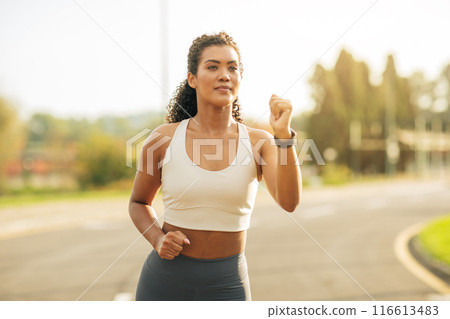 A woman clad in a sports bra top is engaged in the act of running, showing determination and focus as she moves forward with strength and agility. A woman clad in a sports bra top is engaged in the act of running, showing determination and focus as she moves forward with strength and agility. 116613483