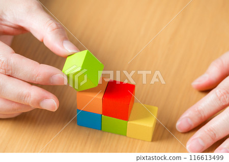 The hands of a person stacking blocks in a staircase pattern 116613499