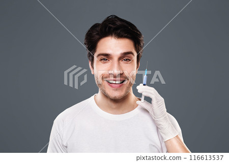 Trendy cosmetics procedure for men. Young man getting beauty injection, grey studio background Trendy cosmetics procedure for men. Young man getting beauty injection, grey studio background 116613537