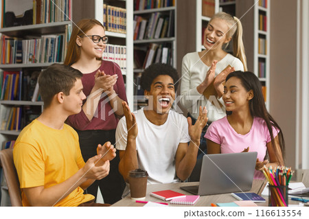 Exam is passed. Emotional afro male student expressing happines, his friends applauding, library interior 116613554