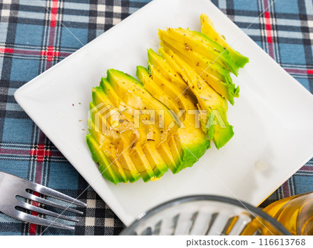 On table there is plate with snack - pieces of avocado pulp. 116613768