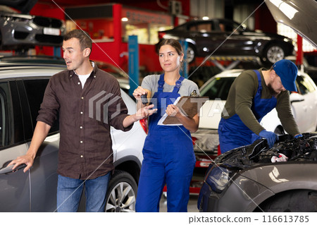 Man explains to girl the car service manager problems of his car. Girl holds paper holder in her hands Man explains to girl the car service manager problems of his car. Girl holds paper holder in her hands 116613785