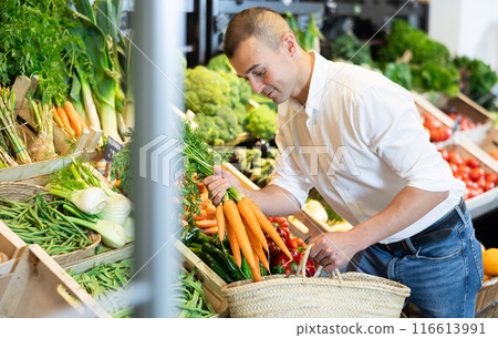 Young man purchaser buying organic carrot in grocery store 116613991