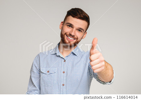 You are cool. Portrait of handsome young guy with thumb up posing isolated on gray studio background 116614014