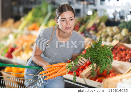 Young girl purchaser buying organic carrot in grocery store 116614085