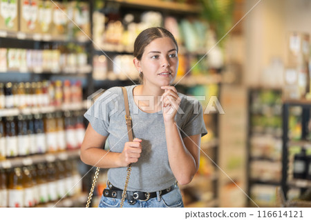 Interested girl exploring shelves at organic foods store Interested girl exploring shelves at organic foods store 116614121