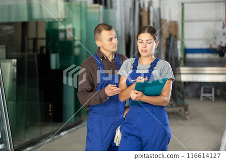 Two glass workshop workers discussing documents 116614127