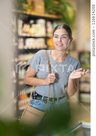 Young female shopper browsing grocery shelves at supermarket Young female shopper browsing grocery shelves at supermarket 116614208