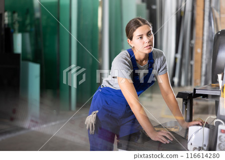 Woman working on CNC glass processing machine at factory 116614280