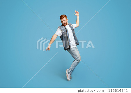 Young cheerful stylish man dancing on tiptoes on blue studio background, copy space, full length shot Young cheerful stylish man dancing on tiptoes on blue studio background, copy space, full length shot 116614541