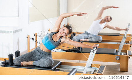 Young girl performing pilates exercises on reformer at group workout 116614547