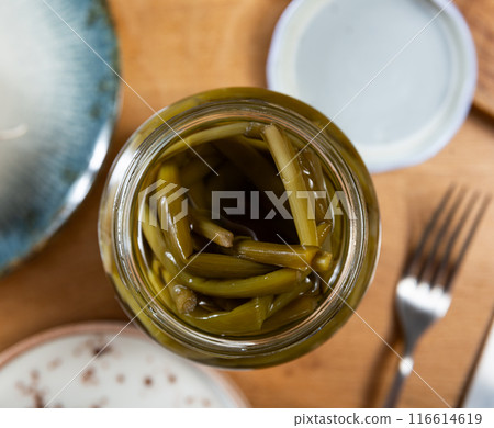 There is open jar with pickled green young ramson shoots on table. There is open jar with pickled green young ramson shoots on table. 116614619