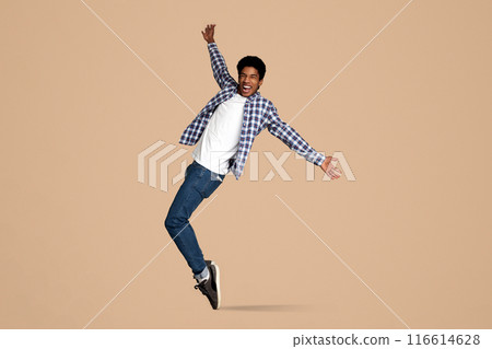 Funny Black Guy Fooling, Standing on Sneakers Toes on White Studio Background 116614628