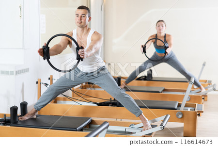 Man performing pilates exercises with resistance ring on reformer Man performing pilates exercises with resistance ring on reformer 116614673