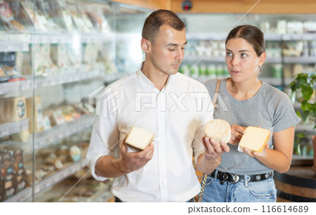 Positive young couple choosing cheese in large supermarket 116614689