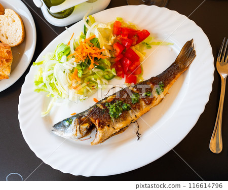 There is plate with fried whole carcass zander fish and mix vegetable salad on table There is plate with fried whole carcass zander fish and mix vegetable salad on table 116614796