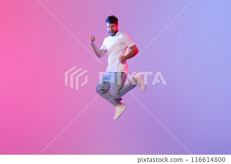 A man wearing a white t-shirt jumps high in the air, displaying a sense of freedom and energy. The image captures the dynamic movement and the crisp white fabric contrasting against the sky. 116614800