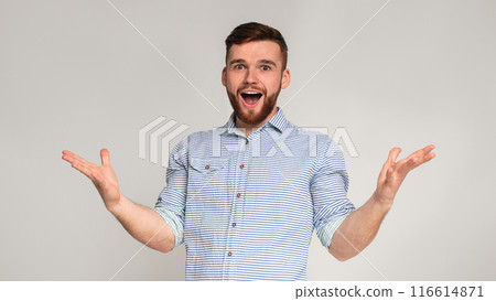 Hey you. Young exited bearded man raising hands and happy screaming on grey studio background, panorama Hey you. Young exited bearded man raising hands and happy screaming on grey studio background, panorama 116614871