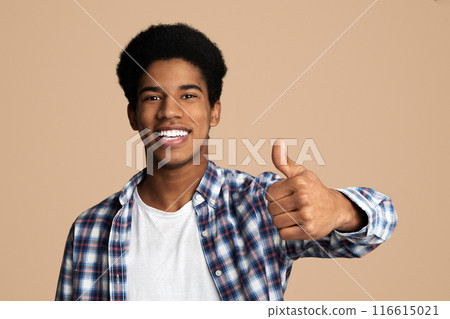 Overjoyed african guy showing thumb up and widely smiling, white studio background Overjoyed african guy showing thumb up and widely smiling, white studio background 116615021