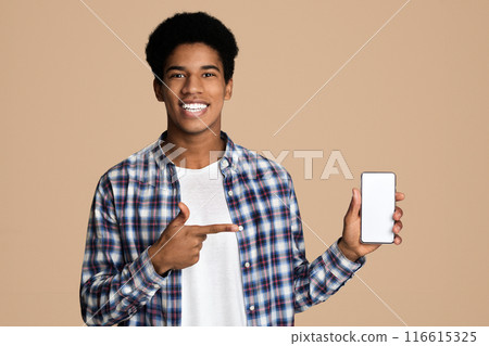 Smiling african-american guy holding smartphone with blank screen and point at it, copy space Smiling african-american guy holding smartphone with blank screen and point at it, copy space 116615325