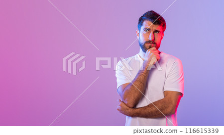 A young man dressed in a white t-shirt stands against a vivid gradient background, appearing thoughtful as he rests a hand on his chin in contemplation, copy space 116615339