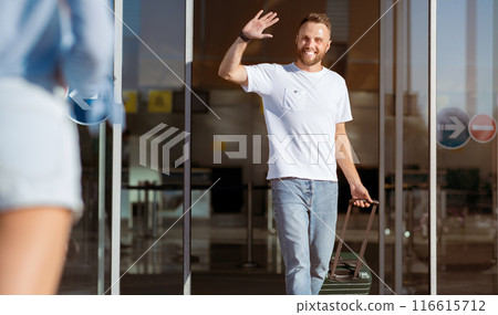 Arriving at airport. Young man greeting girlfriend, walking with suitcase 116615712