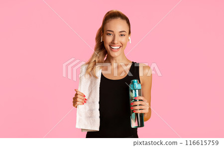 Fitness Lifestyle. Smiling Lady In Wireless Earphones Listening To Music Holding Bottle Of Water And Towel Standing Over Yellow Background. 116615759