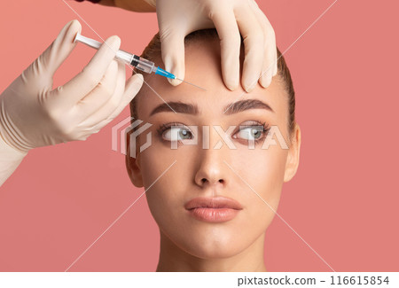 Skin Lifting Injection. Young Woman Receiving Botox Beauty Injection In Forehead Standing Over Pink Background. Studio Shot 116615854