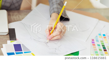 Fashion caree. Designer drawing sketches for clothes with color swatches on table 116615881