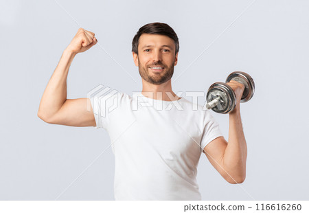 Workout Concept. Strong Man Holding Dumbbell Showing Biceps On White Studio Background. Workout Concept. Strong Man Holding Dumbbell Showing Biceps On White Studio Background. 116616260