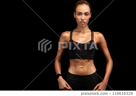 Determined Fitness Girl Looking At Camera Posing Over Black Studio Background. Copy Space Determined Fitness Girl Looking At Camera Posing Over Black Studio Background. Copy Space 116616329