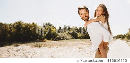 Happy father and daughter playing and carrying on back, walking in nature 116616330